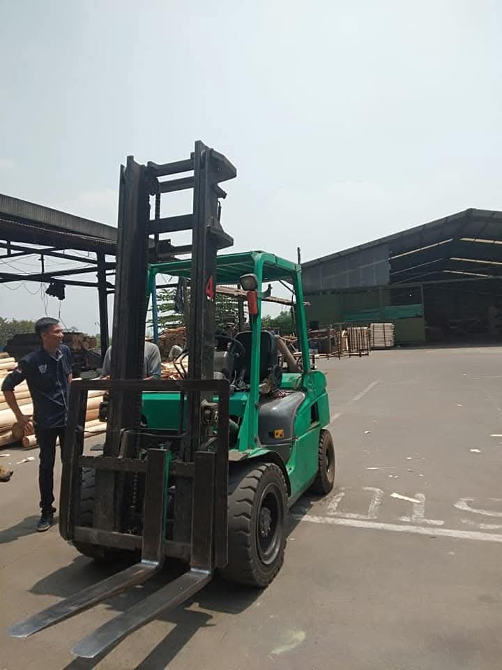 Forklift hijau siap operasional di area pabrik outdoor
